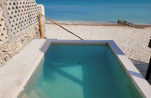Chuburna Puerto Cottage | Pasilla suite. Ocean view glass doors to the turquoise water, 13foot Tv screen