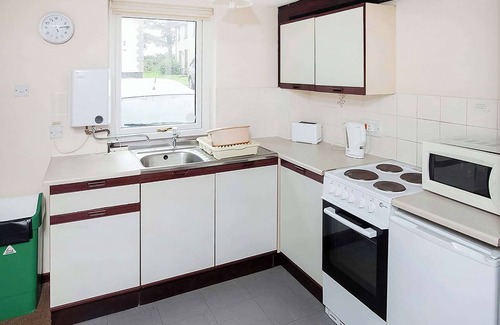 Chysauster Cottage | This silver cottage features an open kitchen, dining room, and living room.