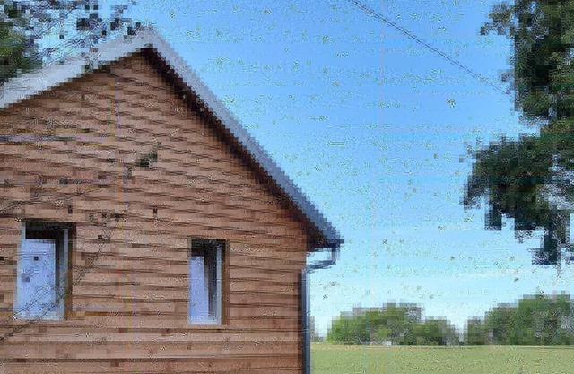 In the middle of nature, wooden house on the edge of the forest with a view of meadows and fields