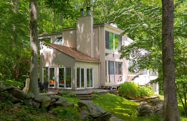 Luxurious midcentury modern glass house in the woods, chefs kitchen & great art