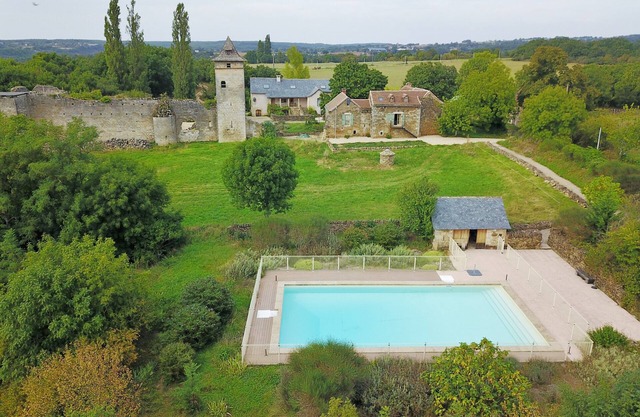 Two houses with a large swimming pool next to the ruins of a medieval castle